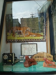 薩摩菓子処 虎屋本舗のお店の外から見えるショーケースに賞状や楯が飾られている