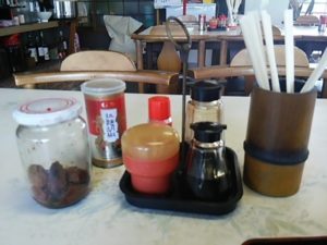鳴子前食堂のテーブルセットは梅干し、拉麺胡椒、七味とうがらし、醤油2種類、割り箸、つまようじ