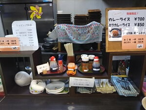 重吉そば七ッ島店の受け取り口近くに、調味料や取り皿などが並ぶ