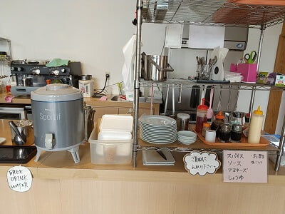 GREEN TEA CAFE AOZORA(グリーンティーカフェあおぞら)の正面カウンターにはセルフで調味料やお冷、ホットウーロン茶に新聞まである