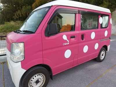 ごはん家(GOHANYA)の店名の入ったピンクの車
