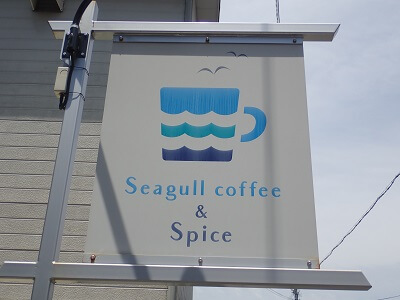 Seagull coffee & Spice（シーガルコーヒー＆スパイス）の2台の駐車場の間にイラスト入りの看板あり
